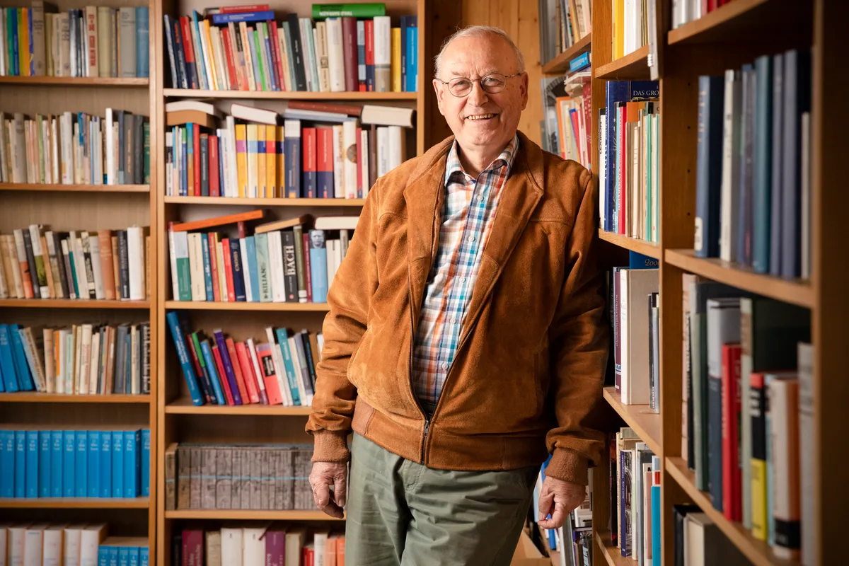 Ein Herr steht in einem Zimmer voller Bücher.